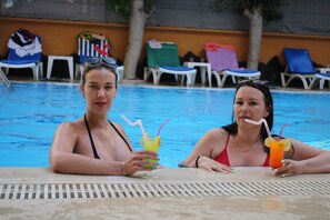 Una piscina al aire libre, sombrillas, sillones reclinables de piscina