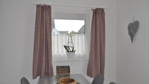 A dining area with a table, chairs, a potted plant, a wooden sign labeled "LETTERS," and a window with checkered curtains. - Romantic quiet chalet with a beautiful garden (Algolsheim)