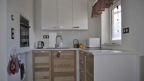 A compact kitchen with white cabinets, a built-in oven, a microwave, and a sink. - Romantic quiet chalet with a beautiful garden (Algolsheim)