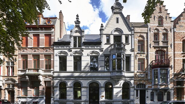 A historic building with a prominent entrance, large windows, and a corner location. - Kind of OJ (Bruges)