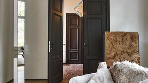 A bedroom with a bed, a mirror, a wooden door, and a rug. - Kind of OJ (Bruges)