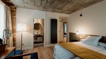 Una camera da letto moderna con soffitto in legno, un letto grande con una coperta gialla, una scrivania con una sedia, una lampada e una pianta in vaso.