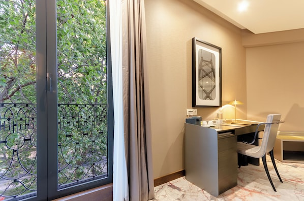 Una habitación de hotel moderna con escritorio, silla y un ventanal con vistas a zonas verdes.
