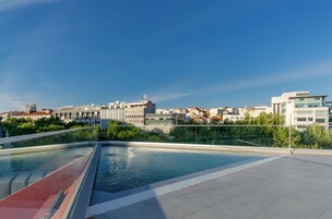 Una piscina al aire libre, sombrillas, sillones reclinables de piscina