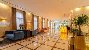 Vestíbulo de hotel con mostrador de recepción, zona de estar y una planta grande.
