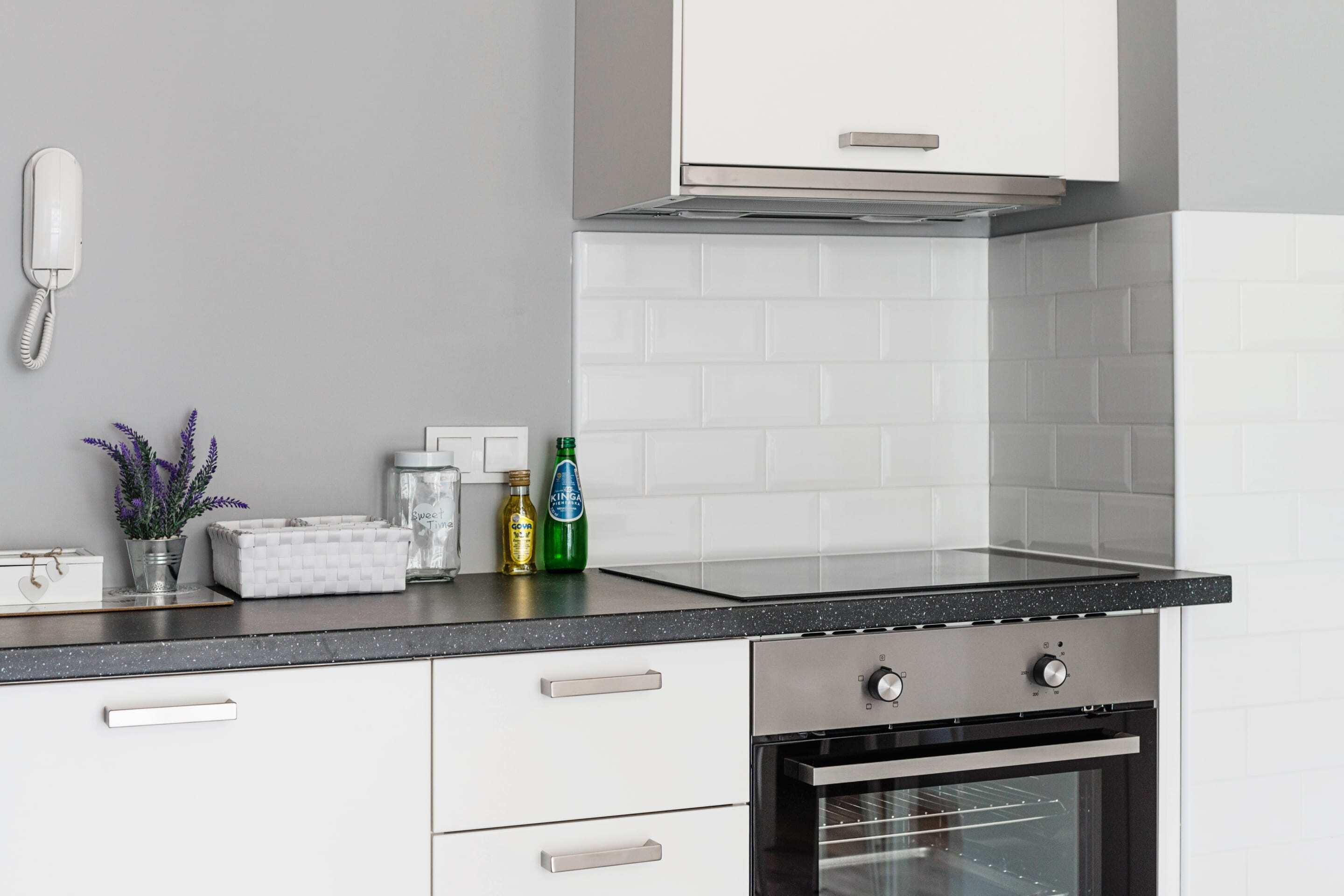 A modern kitchen with white cabinets, a black countertop, and a built-in oven.