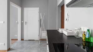 A modern kitchen with grey walls, a black countertop, and a white door. - Warszawa-Wlochy Brilliant Apartment (Warsaw)