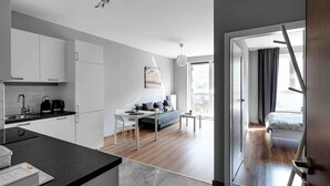 A modern apartment with a kitchen, dining area, and a living room with a sofa and a small table. - Warszawa-Wlochy Brilliant Apartment (Warsaw)