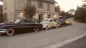 A row of vintage cars parked in front of a building with a stone facade and a sign that reads "LAUREN". - Auberge de Teissieres (Teissières-lès-Bouliès)