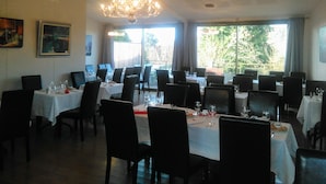 A dining area with tables set for service, a chandelier, and large windows offering a view of the outdoors. - Auberge de Teissieres (Teissières-lès-Bouliès)