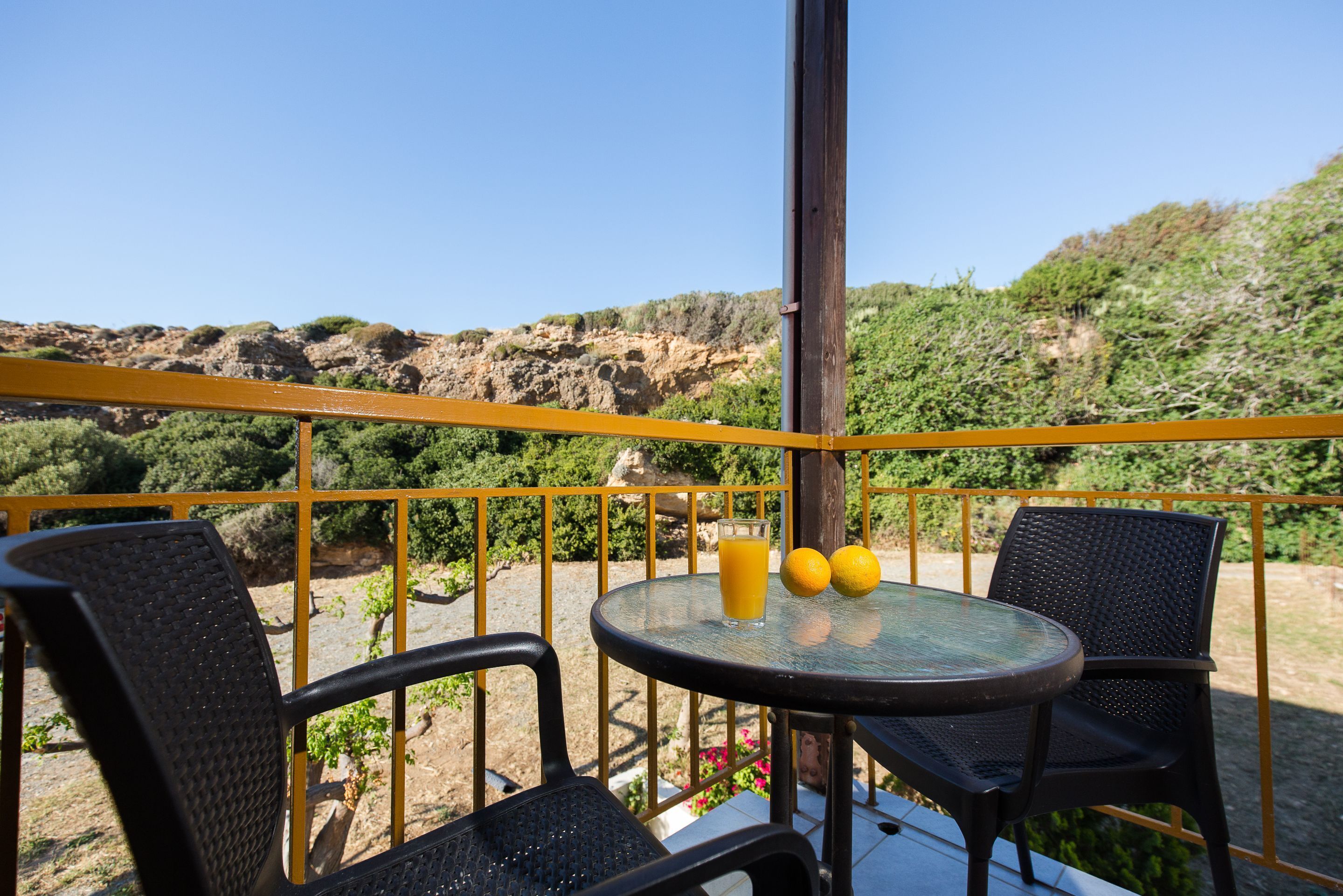 A balcony with two chairs, a round table, and a glass of orange juice.