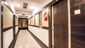 A hotel corridor with a fire extinguisher mounted on the wall, a door with a number plate, and a light switch. - OYO 14194 Hotel Deccan Lodging and Boarding (Hyderabad)