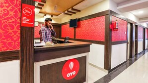 A reception desk with a red and white color scheme, a clock, and a CCTV surveillance sign. - OYO 14194 Hotel Deccan Lodging and Boarding (Hyderabad)