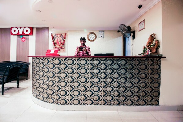 A reception desk with a patterned wallpaper, a clock, and a statue on the wall. - OYO 15140 Hotel Priya Residency (Hyderabad)