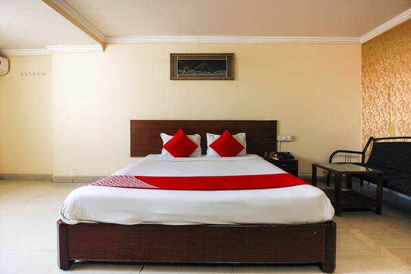 A hotel room with a large bed, a nightstand, a chair, and a framed picture on the wall. - OYO 15140 Hotel Priya Residency (Hyderabad)