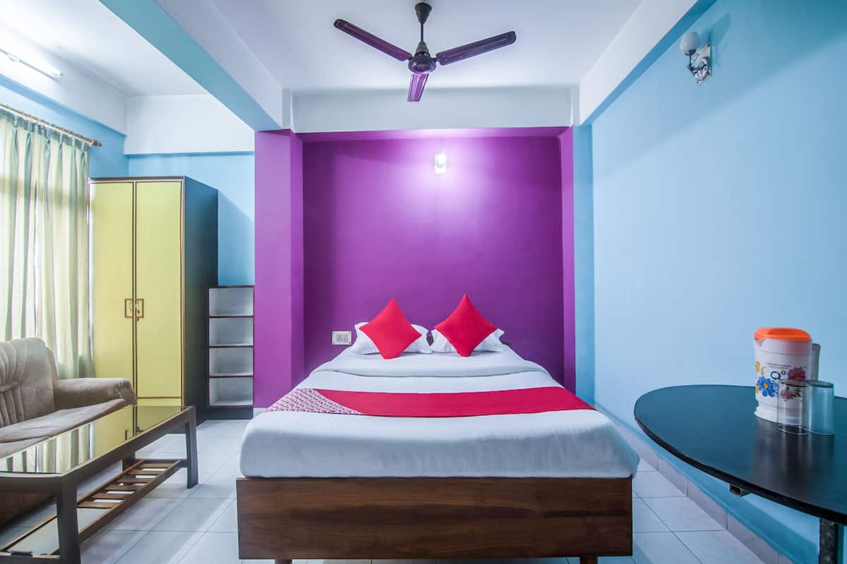 Een slaapkamer met een bed, een stoel, een tafel, een plafondventilator en een kledingkast.