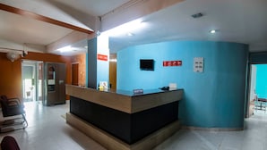 A reception desk with a blue wall, a clock, and a sign indicating a 24-hour service. - OYO 14737 LG Towers (Guwahati)