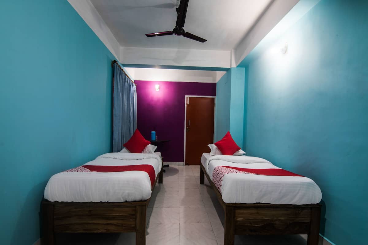 Een hotelkamer met twee houten bedden, een plafondventilator en een paarse muur.