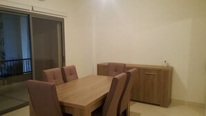 A dining area with a wooden table and six chairs, a wooden cabinet, and a sliding glass door leading to a balcony. - Achrafieh 219 (Beirut)