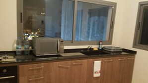 A kitchen with a microwave, sink, and wooden cabinets. - Achrafieh 219 (Beirut)