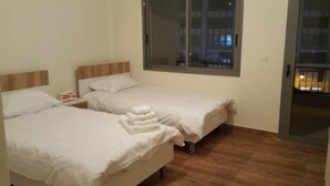 A room with two beds, a window, and a door. - Achrafieh 219 (Beirut)