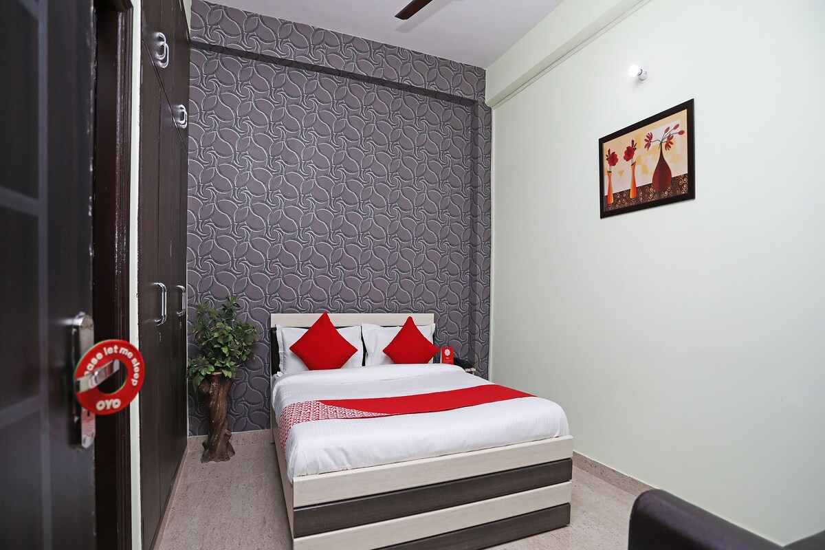 A bedroom with a bed, a potted plant, and a door with a sign.
