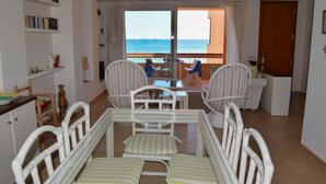 Une chambre avec un balcon, des meubles blancs, une bibliothèque et une vue sur la mer.