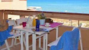 Un balcon avec une table dressée pour deux personnes, donnant sur la mer.