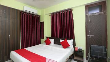A bedroom with a bed, curtains, a wardrobe, and a door.