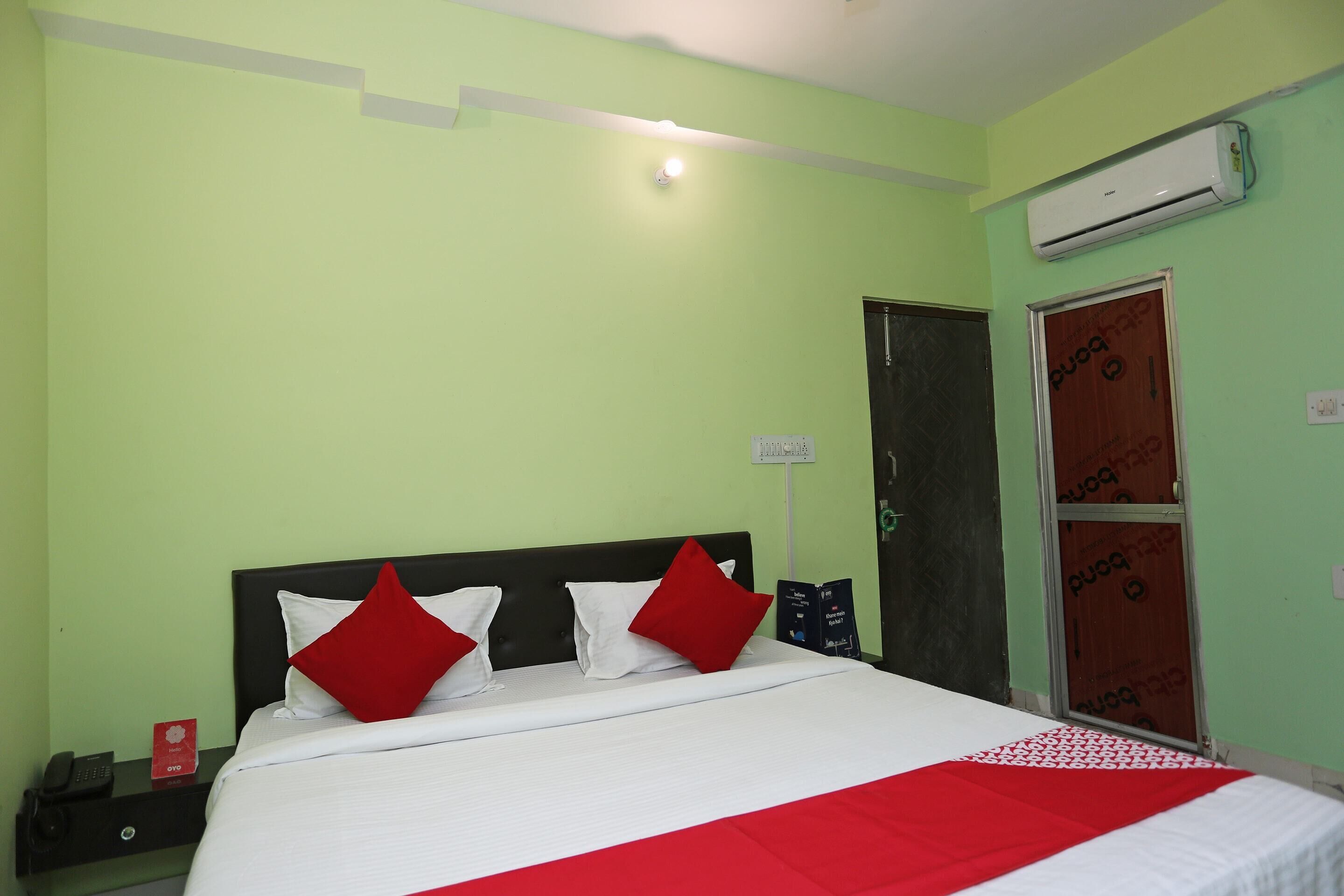 Una habitación de hotel con una cama, una mesita de noche, un teléfono, aire acondicionado y una puerta.