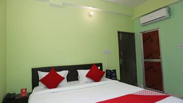 Una habitación de hotel con una cama, una mesita de noche, un teléfono, aire acondicionado y una puerta.