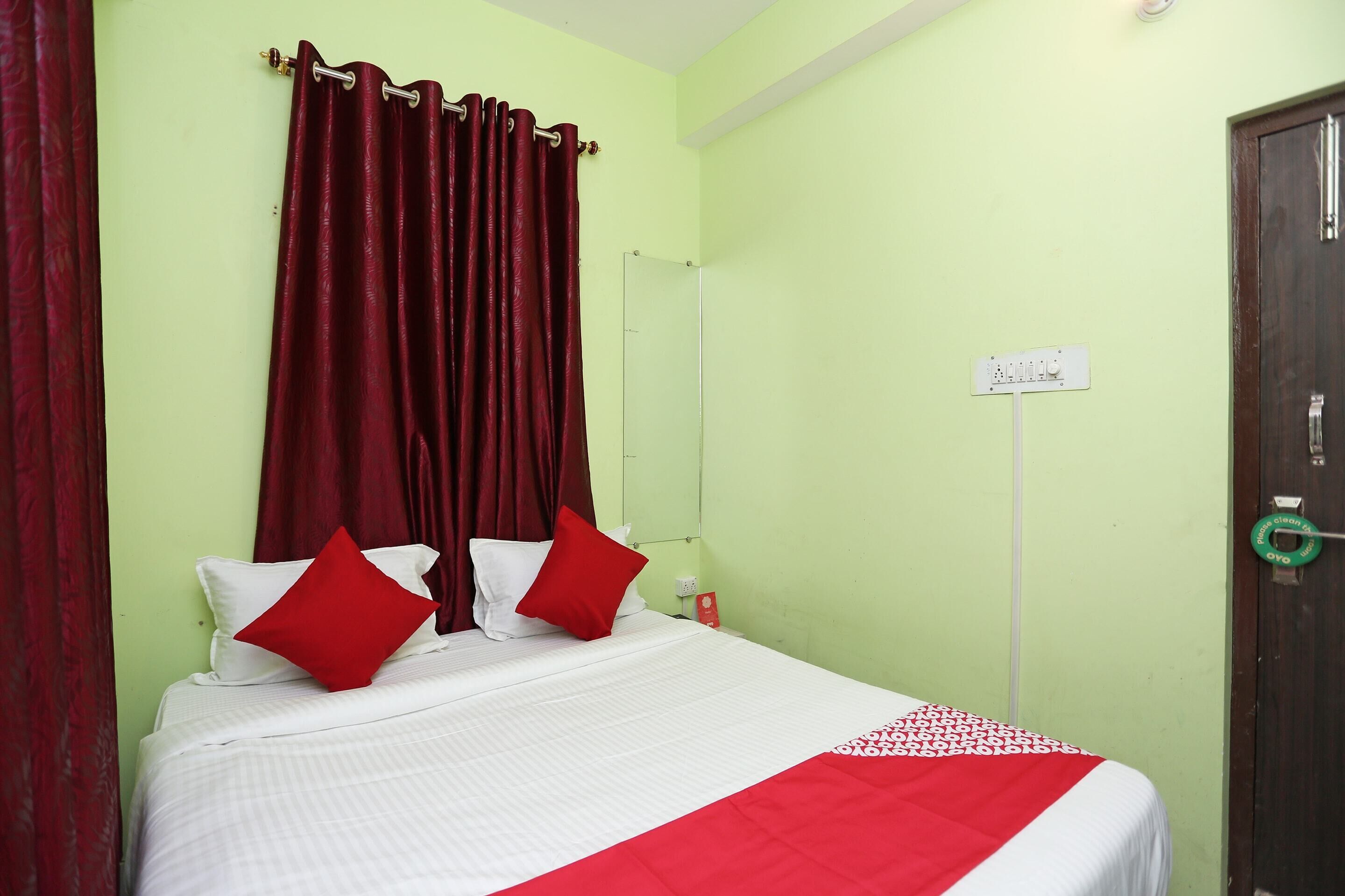 Une chambre d’hôtel avec un lit, des rideaux rouges et un mur vert.