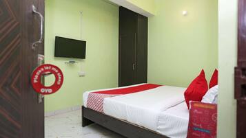 Een kamer met een bed, een aan de muur bevestigde televisie en een deur met een bordje.