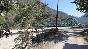 A green metal bridge over a river, surrounded by trees and hills. - OYO 26673 The Royal Rishikesh - Campsite (Rishikesh)