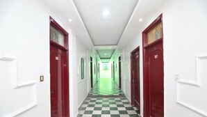 A hotel hallway with checkered flooring, red doors numbered 206 and 207, and white walls.