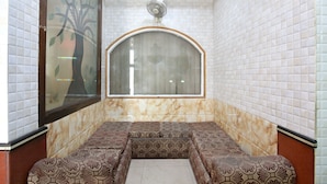 A room with a patterned bench, a large window with a tree design, and a ceiling fan.