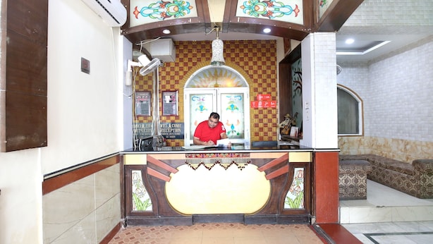 A reception area with a counter, a man behind it, and a decorative wall.