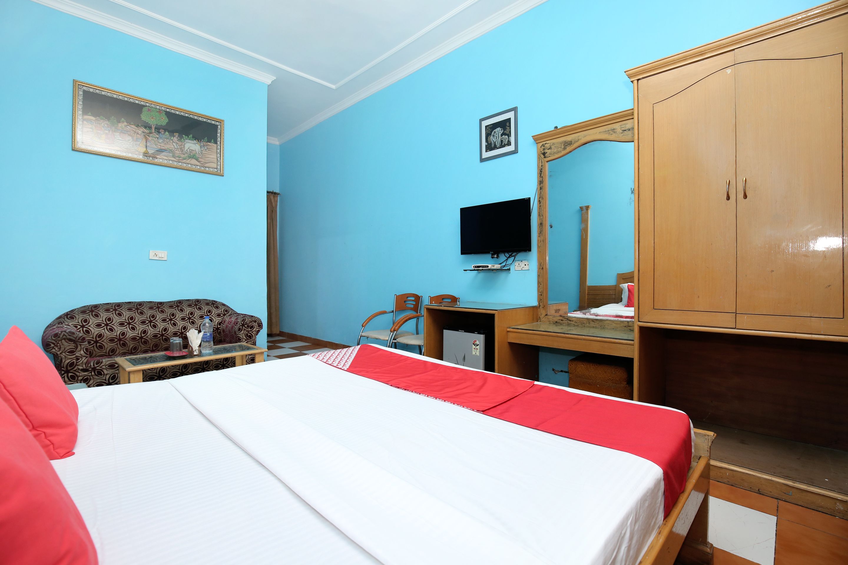 Une chambre d’hôtel comprenant un lit, un bureau, une télévision, une armoire et un canapé.