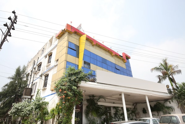 A multi-story building with a white facade, blue windows, and a yellow stripe.