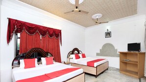 A hotel room with two beds, a ceiling fan, a TV on a wooden stand, and a marble floor.