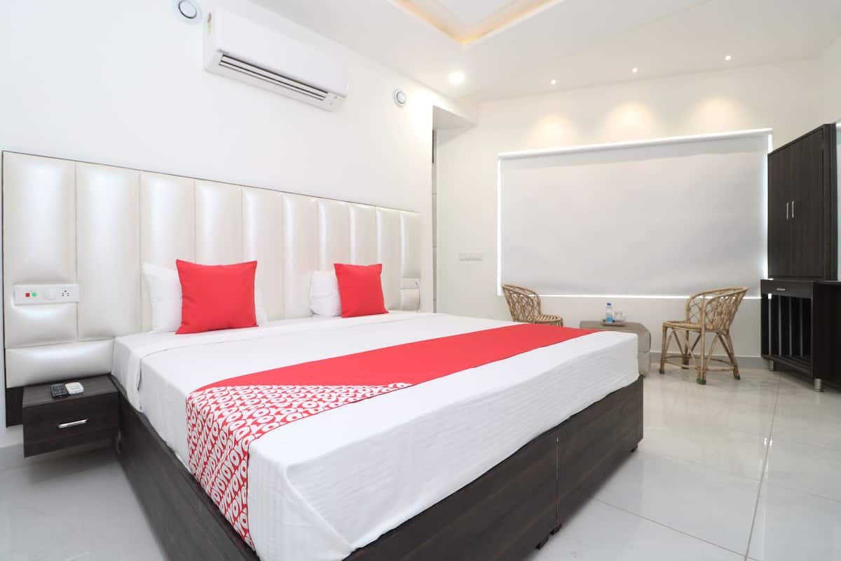 A modern hotel room with a large bed, a flat-screen TV, a small table, and a chair.