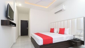 Un dormitorio moderno con una cama grande, un televisor montado en la pared y una mesita de noche con un teléfono.