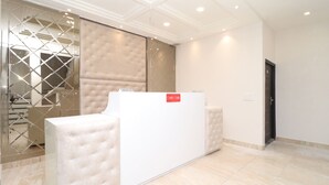 Un área de recepción con un mostrador blanco, una partición de vidrio y una puerta.