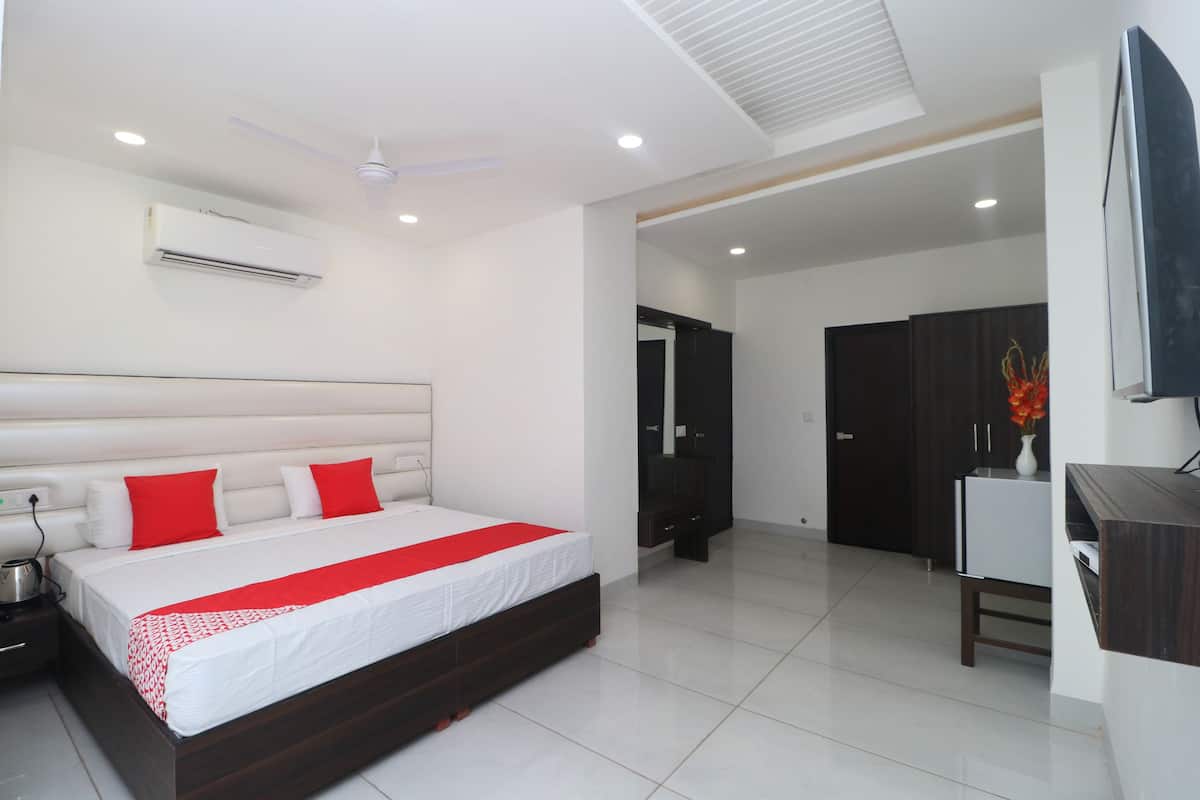A modern hotel room with a large bed, a flat-screen TV, a desk, and a wardrobe.