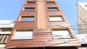Un edificio de varios pisos con un diseño arquitectónico moderno, que destaca un elemento vertical central y múltiples ventanas.