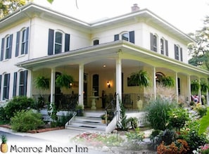 A large, two-story house with a covered porch and a fountain. - Monroe Manor Inn (South Haven)