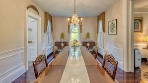 Un comedor formal con una larga mesa de madera, sillas ornamentadas, un candelabro y un jarrón con flores.