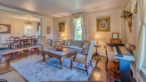 Un salón espacioso con un piano, un sofá, una mesa de centro y una zona de comedor con sillas y una mesa.