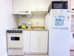 A compact kitchen with a stove, sink, and microwave.