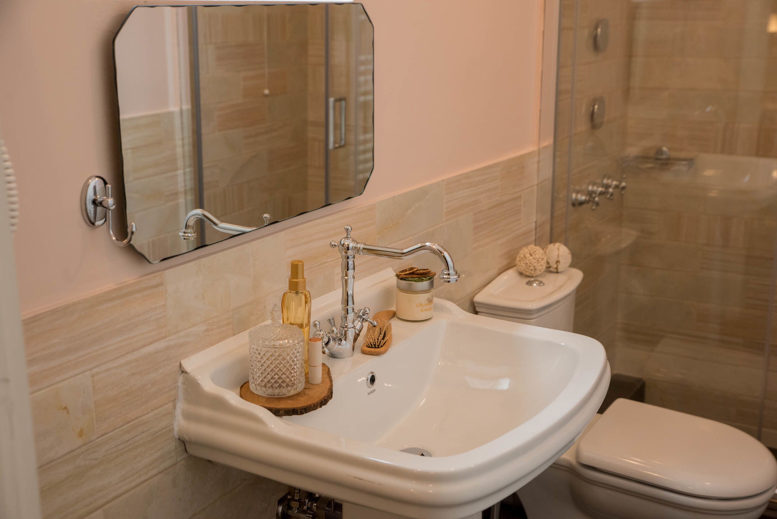 A bathroom with a white sink, a mirror, a toilet, and a shower area.